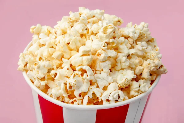 Popcorn in classic striped bucket on pink background. Paper box,