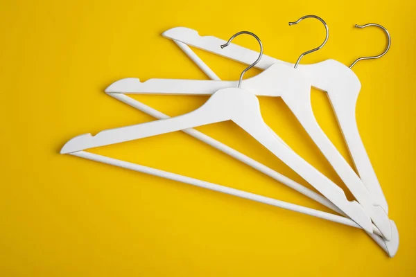 White clothes hangers on yellow background. Store concept.. Fashion concept. Stock of empty clothes hanger. Flat lay. Copy space for text.
