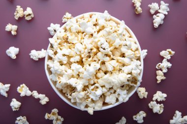 Kırmızı arka plan üzerinde yukarıdan görüntülenen testy sıcak patlamış mısır. Üst te. Enterteinment kavramı