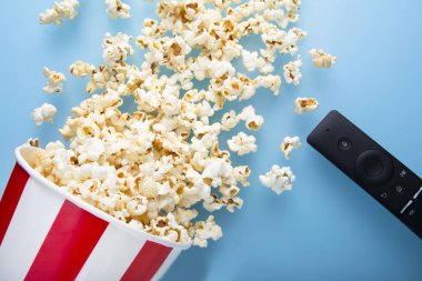 Tv kaldırmak ile mavi bir arka plan üzerinde dökülen patlamış mısır üst görünümü. Sinema, film konsepti. Close