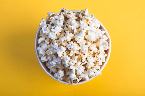 Vista superior de palomitas de maíz sobre fondo amarillo. Snack para una película, una idea para una comida. Primer plano, vista superior. Copia espacio para texto. Copa de papel para palomitas de maíz . —  Fotos de Stock