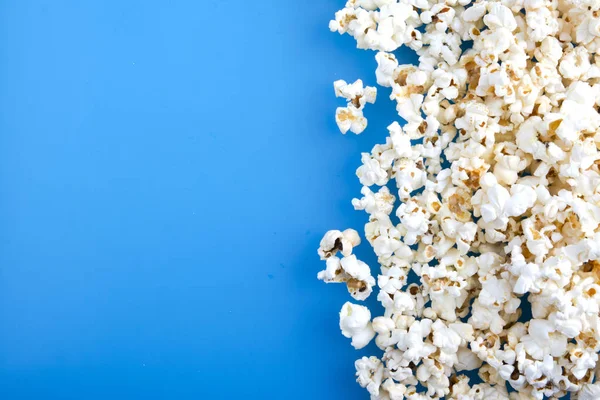 Chutný solený popcorn izolovaný na modrém pozadí. Kopírovat prostor pro text — Stock fotografie