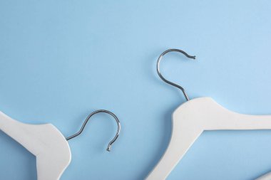 Bazı beyaz elbise askıları mavi bir arka plan üzerinde izole. Metin için alan kopyalayın. Düz yatıyordu. Fasion kavramı.