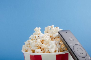 Patlamış mısır ile Çizgili kağıt bardak, Tv uzak ve mavi arka plan, üst görünüm metin için alan. Sinema izlemek