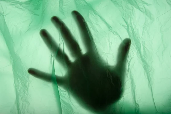 Somebody hand in plastic bag. Murder concept. Concept view. Close up. Soft green texture