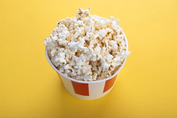 Pruhovaný papírový pohár s popcornem. Chutný popcorn na žlutém pozadí. Svačinka pro film, nápad na jídlo. Zblízka, pohled shora. Kopírovat prostor pro text. — Stock fotografie