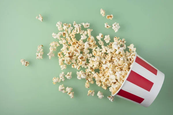 Proužkovaný pruhovaný papír s lahodnou čerstvou popcornem na zeleném pozadí. Pojetí zábavy. — Stock fotografie