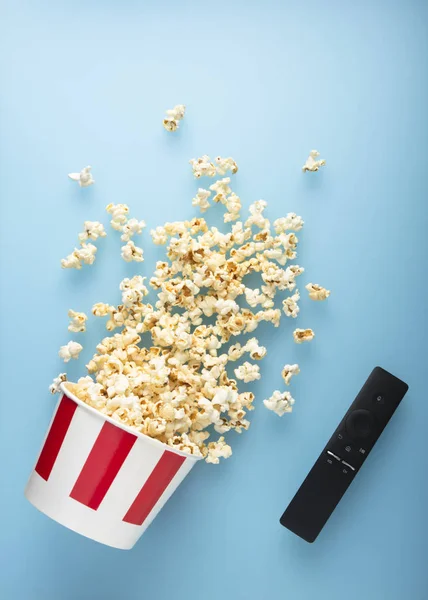 Palomitas de maíz derramadas sobre un fondo azul con eliminación de TV. Concepto de entretenimiento. Vista superior . —  Fotos de Stock