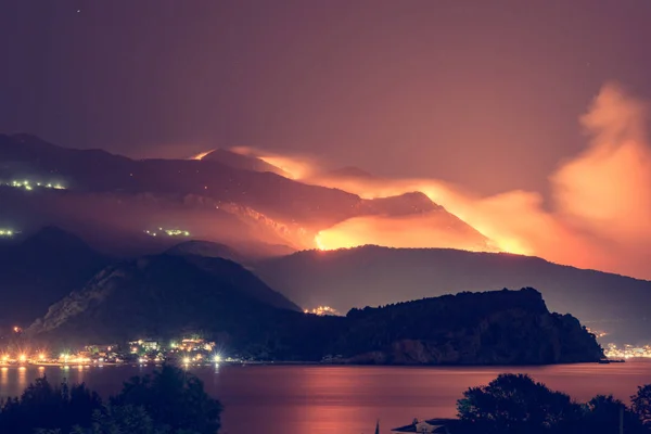 Wild fire blazing on hills above sea town. — Stock Photo, Image