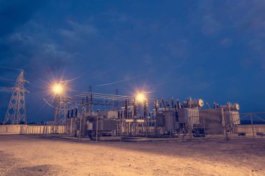 Geceleri ışıkları tarafından aydınlatılmış elektrik trafo merkezi.