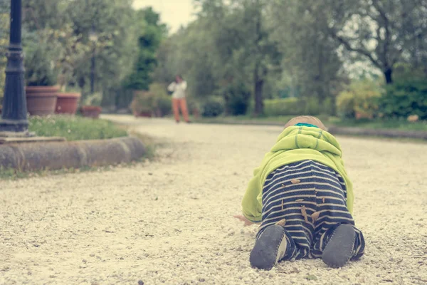 Vista posteriore di un bambino che striscia verso sua madre all'aperto . — Foto Stock