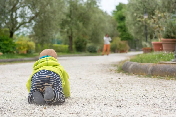 Rückansicht eines Babys, das im Freien auf seine Mutter zukriecht. — Stockfoto