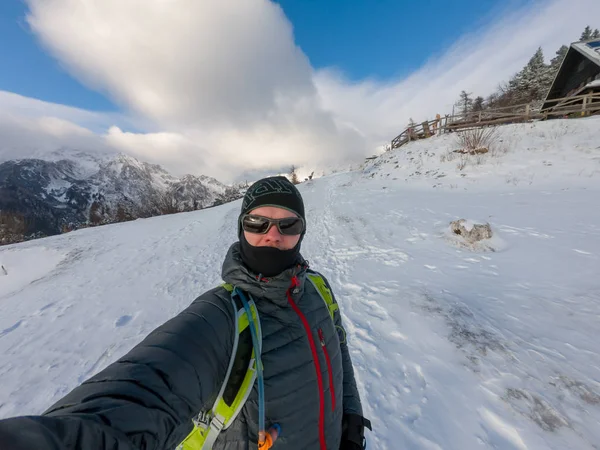 Альпинист делает зимнее селфи, позируя на заснеженных холмах . — стоковое фото