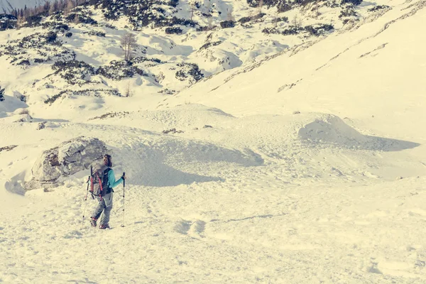 Alpinista feminina descendo no vale da montanha cruzando flocos de neve . — Fotografia de Stock