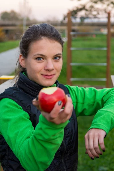 Fitness trainer biedt een appel op outdoor sportschool. — Stockfoto