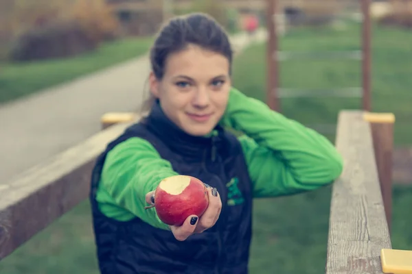 Fitnes trainer oferecendo uma maçã no ginásio ao ar livre . — Fotografia de Stock