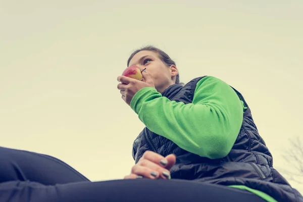 Mujer atlética tomando un bocadillo de fruta saludable durante el ejercicio al aire libre . — Foto de Stock