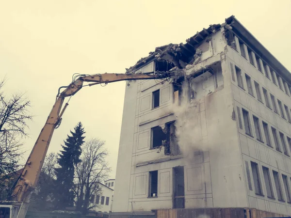 Demolire un vecchio edificio obsoleto con macchinari pesanti . — Foto Stock