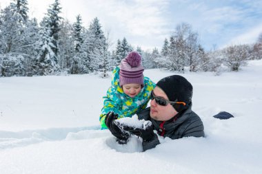 Baba ve kızı taze karda oynarken.