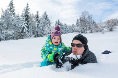 Baba ve kızı taze karda oynarken. Etkin babalık.