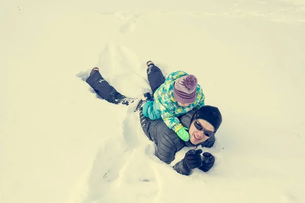 Far och dotter spelar i nysnö. — Stockfoto