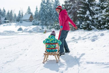 Anne kızı üzerinde ahşap kızak çekerek.