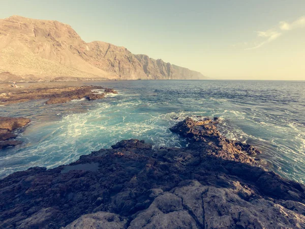 Golven spatten in vulkanische kust bij zonsondergang. — Stockfoto