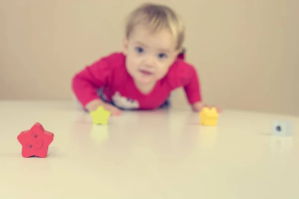 Симпатична блондинка в червоній сукні грає з іграшками за столом . — стокове фото