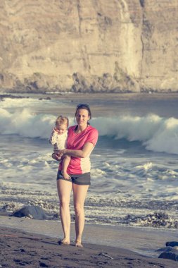 Anne ve kızı kumsalda poz.