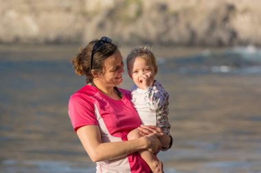 Anne ve kızı kumsalda poz.