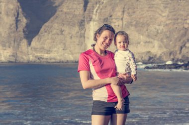 Anne ve kızı kumsalda poz.