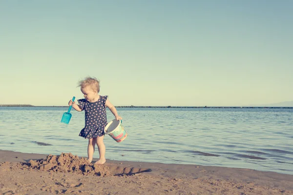 Menina bonito jogando na praia de areia e explorando . — Fotografia de Stock