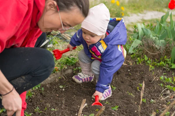 Klein meisje het verkennen van de tuin en helpen met de lente reiniging. — Stockfoto