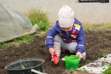 Küçük kız bahçe keşfetmek ve bahar temizliği ile yardımcı.