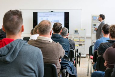 İş sunumunda dinleyiciler konuşma yapan kişiyi dinliyor.
