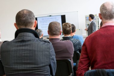 İş sunumunda dinleyiciler konuşma yapan kişiyi dinliyor.