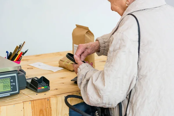 Idosa pagando alguns produtos orgânicos no balcão da loja . — Fotografia de Stock