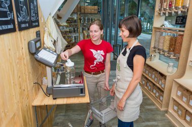 Kadın esnaf sıfır atık deposunda bir müşteri yardım.