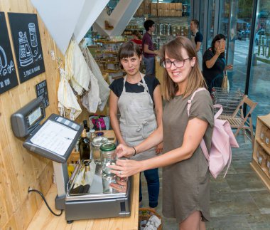 Kadın esnaf sıfır atık deposunda bir müşteri yardım.