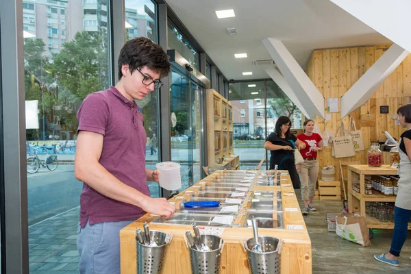 Young male shopper bulk shopping in zero waste store.