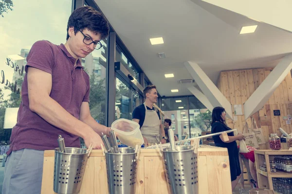 Young male shopper bulk shopping in zero waste store.