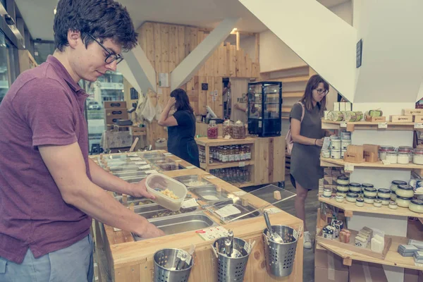 Young male shopper bulk shopping in zero waste store.