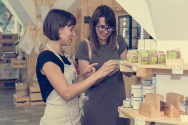 Kadın esnaf sıfır atık deposunda bir müşteri yardım.