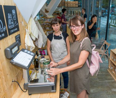 Kadın esnaf sıfır atık deposunda bir müşteri yardım.