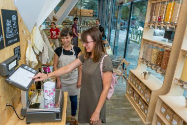 Kadın esnaf sıfır atık deposunda bir müşteri yardım.