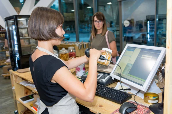 Asistente de tienda que atiende a un cliente en un escritorio . — Foto de Stock