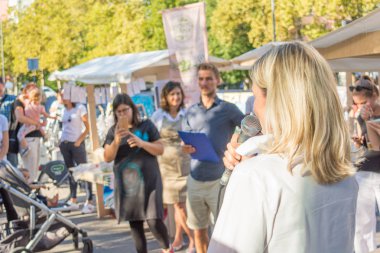 Kadın açık havada canlı seyirci önünde bir konuşma yapıyor.