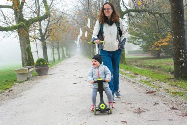Senin annen kızıyla parkta küçük bir scooter 'a biniyor..