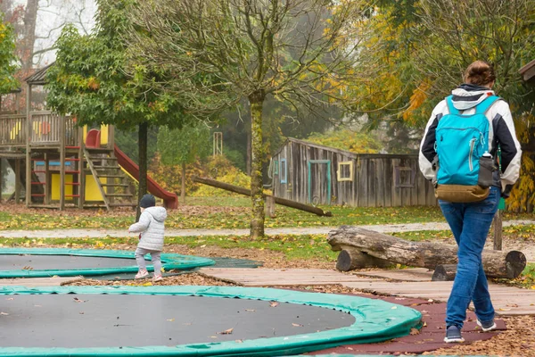 Matka a dcera procházející dětským hřištěm s trampolínami. — Stock fotografie