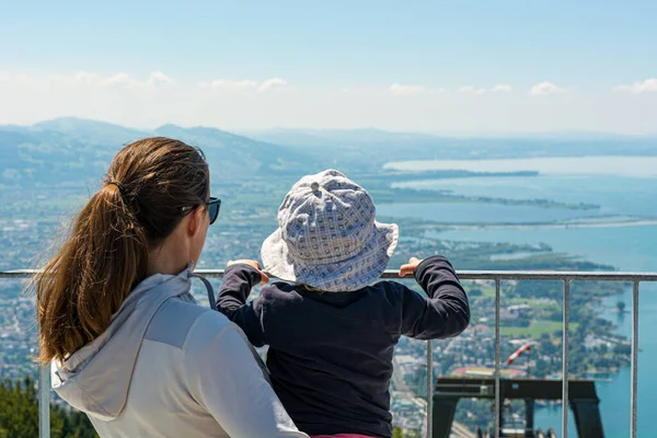 Mãe segurando sua filha enquanto desfruta da vista do lago . — Fotografia de Stock